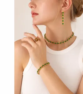 Detailed close-up of gold stainless steel jewelry set with emerald green gemstones