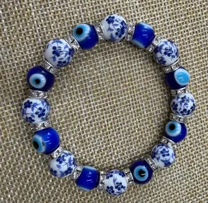 Macro view of blue evil eye beads and floral porcelain beads on an elastic bracelet