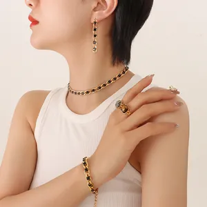 Vintage gold chunky chain jewelry set with black stones worn by a model on white background