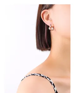 Detailed view of polished silver heart earrings worn by a model in a minimalist style