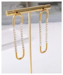 Detail of gold-plated U-shaped earrings with sparkling cubic zirconia on a minimal stand