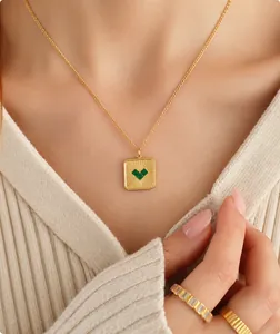 Detail van gouden ketting met vierkante groene hart hanger en zirkonia ringen