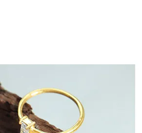 Dettaglio macro di zircone rettangolare incastonato su anello minimalista in ottone dorato