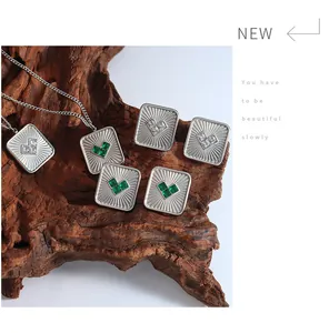 Detail van vintage vierkante oorbellen en ketting met hartvormige groene zirkoon