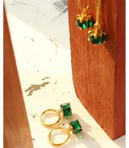 Detail von Vintage-Goldohrringen mit smaragdgrünen Zirkonia auf einer Texturfläche