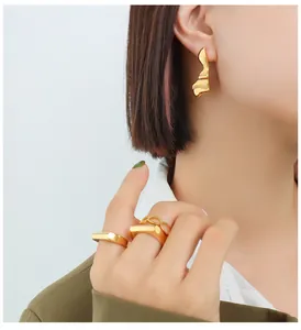 Detail van onregelmatige gouden oorbellen en minimalistische geometrische ringen set