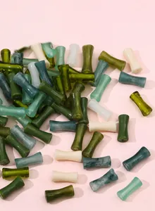 Dettaglio di perle in resina a forma di bambù con trama marmorizzata per gioielli fai-da-te