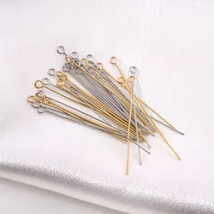 Nahaufnahme von gold- und silbernen Ösenstiften aus Edelstahl für DIY-Schmuck auf weißem Satin