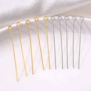 Gold- und silberfarbene Edelstahl-Ösenstifte für DIY-Schmuck auf weißem Porzellan