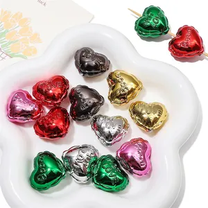 Macro-opname van kleurrijke metalen hartkralen met HOT LOVE-reliëf voor DIY-sieraden