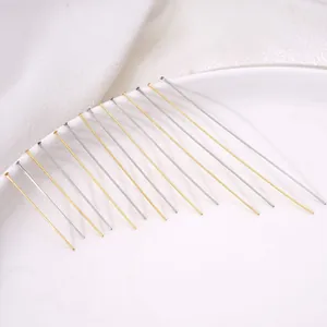Detalle de alfileres de cabeza plana de acero inoxidable plateados y dorados en un plato blanco