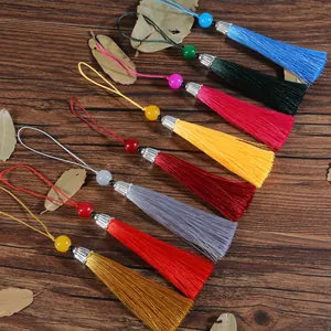 Dettaglio di nappe in seta multicolore con perle e cappucci d'argento su legno