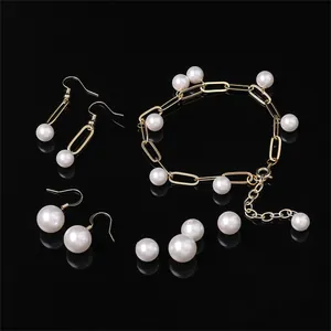 Elegante set di gioielli con perle e catena a graffetta dorata su sfondo nero riflettente