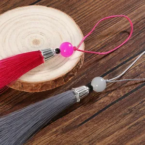Dettaglio macro di nappe in seta fatte a mano con cappucci argentati su legno scuro