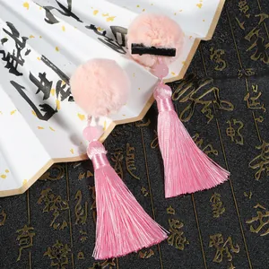 Dettaglio di fermagli per capelli in finta pelliccia rosa con nappe e perle su ventaglio decorato