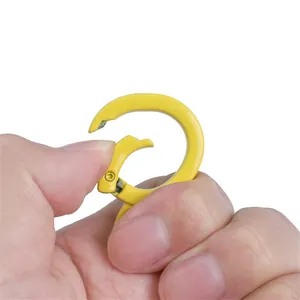 Gele legering konijn veerring gesp met de hand ingedrukt op witte achtergrond