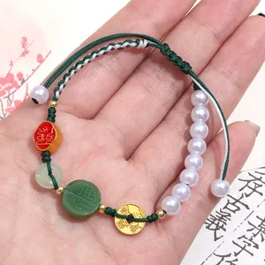 Detailed view of handmade woven bracelet with green jade-like charm and ancient coins