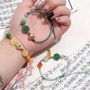 Detailed view of handmade braided bracelets with faux jade beads and good luck charms