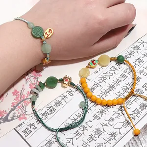 Detailed shot of handmade woven bracelets with jade-like beads and gold Fu pendants