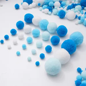 Dettaglio di pompon fai-da-te blu e bianchi in varie dimensioni su sfondo bianco