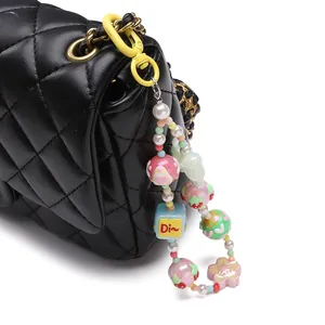Détail d'un porte-clés en perles colorées avec breloque 'Dio' sur un sac en cuir matelassé