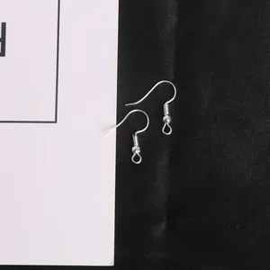 Ganchos para pendientes DIY plateados con cuenta y lazo sobre fondo de raso negro