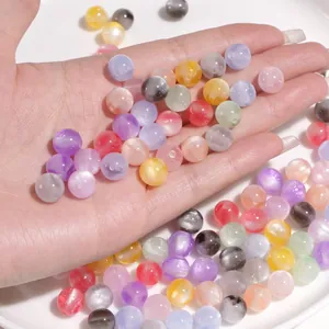 Close-up of colorful resin cat-eye beads for DIY jewelry making held in hand