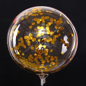 Close-up of transparent balloon filled with golden sequins and white support stick