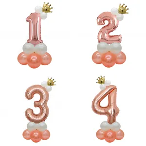 Detail of rose gold number balloons with golden crowns and latex balloon bases