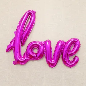 Detail of rose red foil Love script balloon with shiny metallic texture for parties