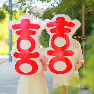 Large 3D Chinese Xi wedding balloons held by a couple in an outdoor garden setting