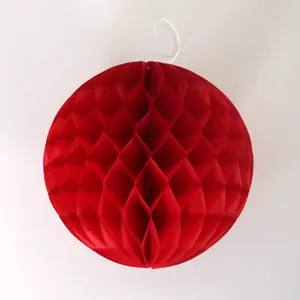 Detailed close-up of a red honeycomb paper ball with hanging string for party decor