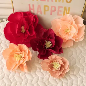 Detailed view of handmade crepe paper flowers in red and peach for wedding wall decor