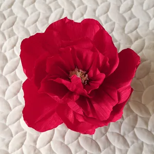 Close-up of deep red crepe paper flower with yellow stamen for wedding decoration