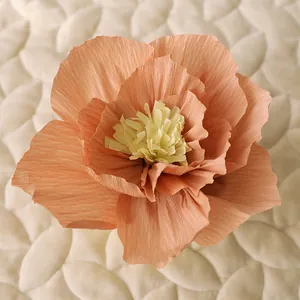 Macro shot of peach crepe paper flower with yellow stamen on quilted background