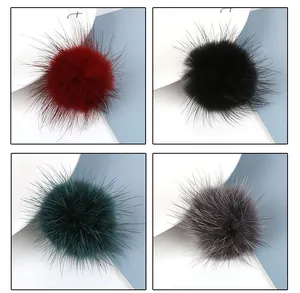 Detail view of plush mink fur pompom pendants in burgundy, black, green, and dark grey