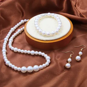 Elegant white glass pearl jewelry set with necklace, bracelet and earrings on wood base