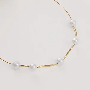 Macro shot of 14K gold filled curved tube beads and pearls on a handmade necklace chain