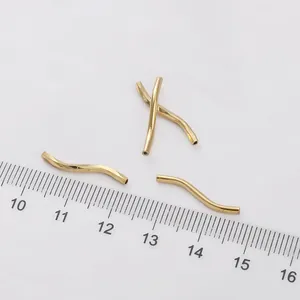 Close-up of four 14K gold-filled S-shaped curved tube beads for jewelry making