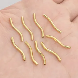 Nine 14K gold filled S-curve spacer beads for DIY jewelry making on a hand palm