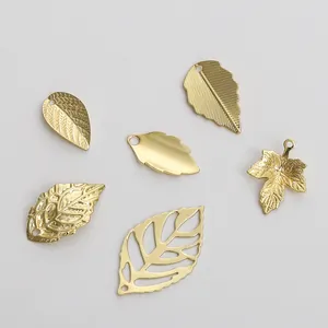 Macro view of 14K gold plated leaf charms with intricate hollow and engraved patterns