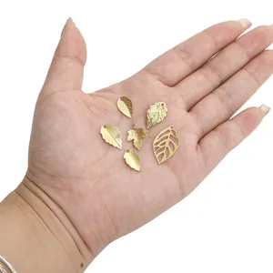 Set of six gold hollow leaf charms for DIY jewelry making displayed on a palm
