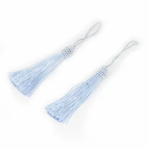 Vue détaillée de deux pompons en soie de polyester bleu clair avec boucles de suspension