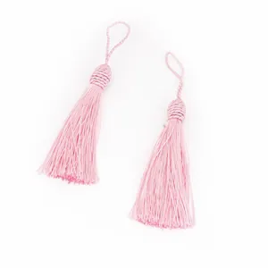 Vue détaillée de glands en polyester rose avec têtes tressées et boucles de suspension
