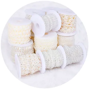 Assorted DIY pearl and rhinestone chain rolls on white spools for garment accessories