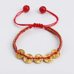 Detail of hand-woven red and gold bracelet with five brass coins and adjustable closure