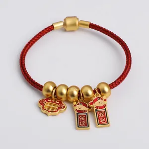 Macro detail of red woven bracelet with gold-plated charms and Chinese fortune symbols