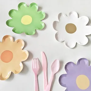 Dettaglio di piatti di carta usa e getta a forma di fiore in colori macaron con posate