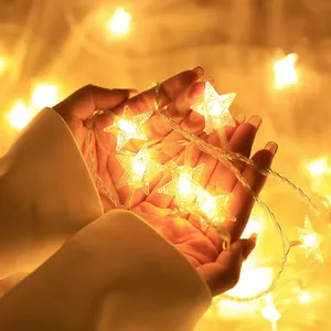 Close-up of star-shaped LED fairy lights emitting warm yellow glow in hands