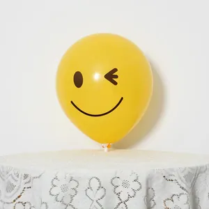 Detail of yellow latex balloon with winking smiley face print and white holder stand